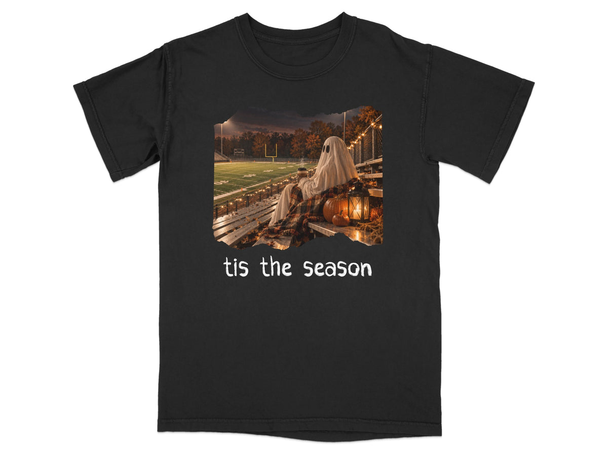 Ghost sitting on bleachers with pumpkin and lantern, text "tis the season".