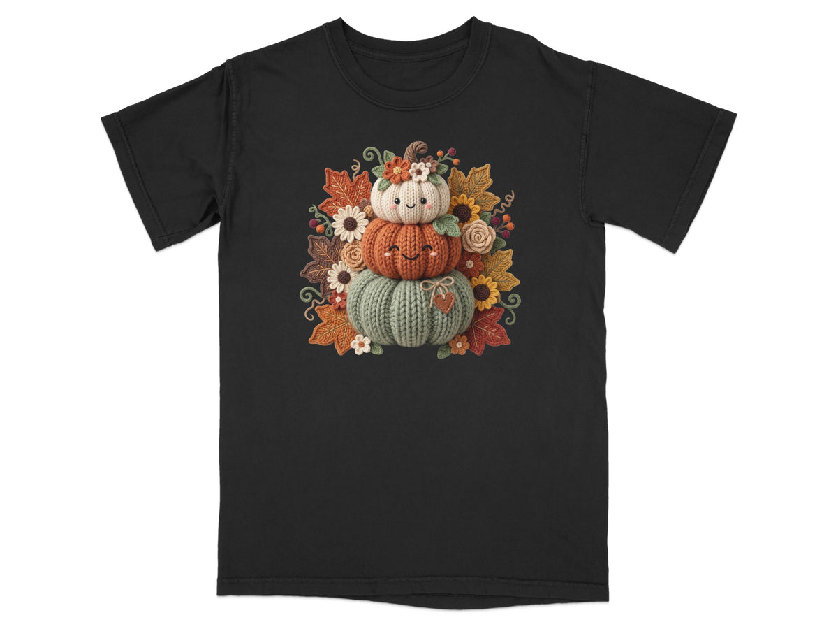 Knitted pumpkin stack with autumn leaves and flowers on a black t-shirt.