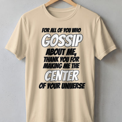 Beige t-shirt with text: "FOR ALL OF YOU WHO GOSSIP ABOUT ME, THANK YOU FOR MAKING ME THE CENTER OF YOUR UNIVERSE."