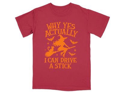 Red t-shirt with orange graphic of witch, cat, bats, and text "Why Yes Actually I Can Drive A Stick."