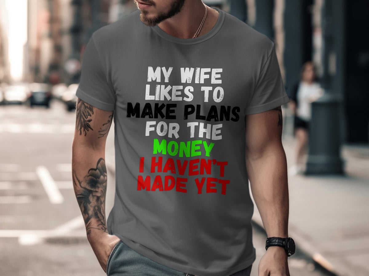 Grey t-shirt with white, green, and red text reading "MY WIFE LIKES TO MAKE PLANS FOR THE MONEY I HAVEN'T MADE YET".