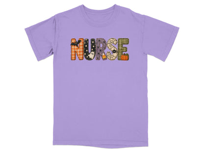 A short-sleeved purple crewneck t-shirt featuring the word NURSE spelled out in patterned Halloween-themed block letters.