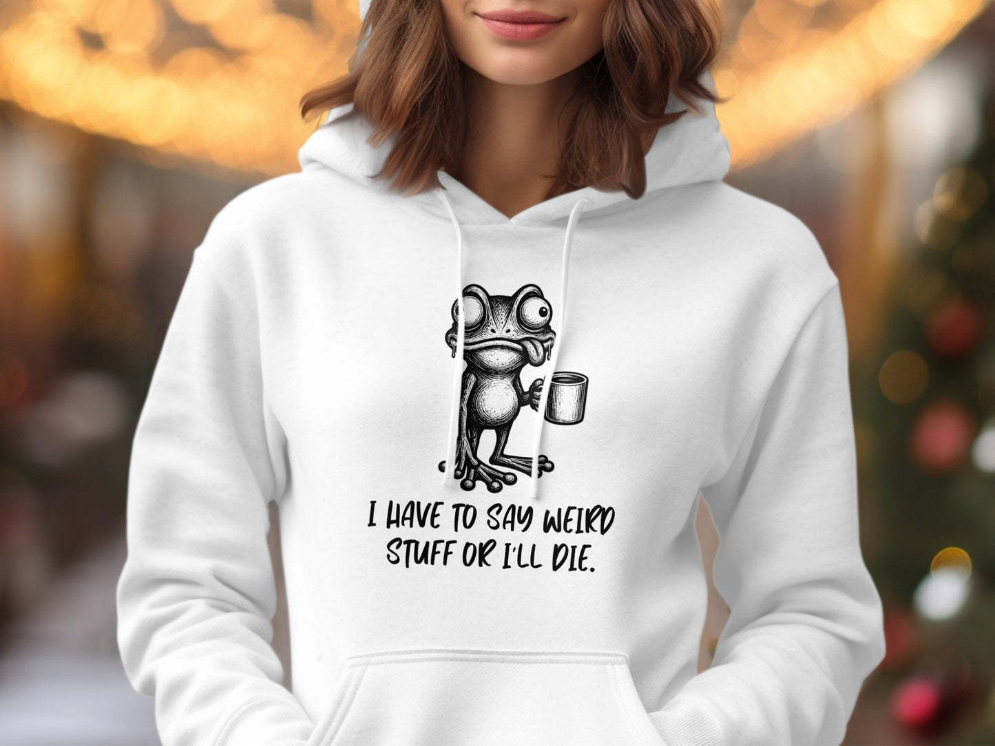 White hoodie with a cartoon frog holding a mug and text that says "I HAVE TO SAY WEIRD STUFF OR I'LL DIE."