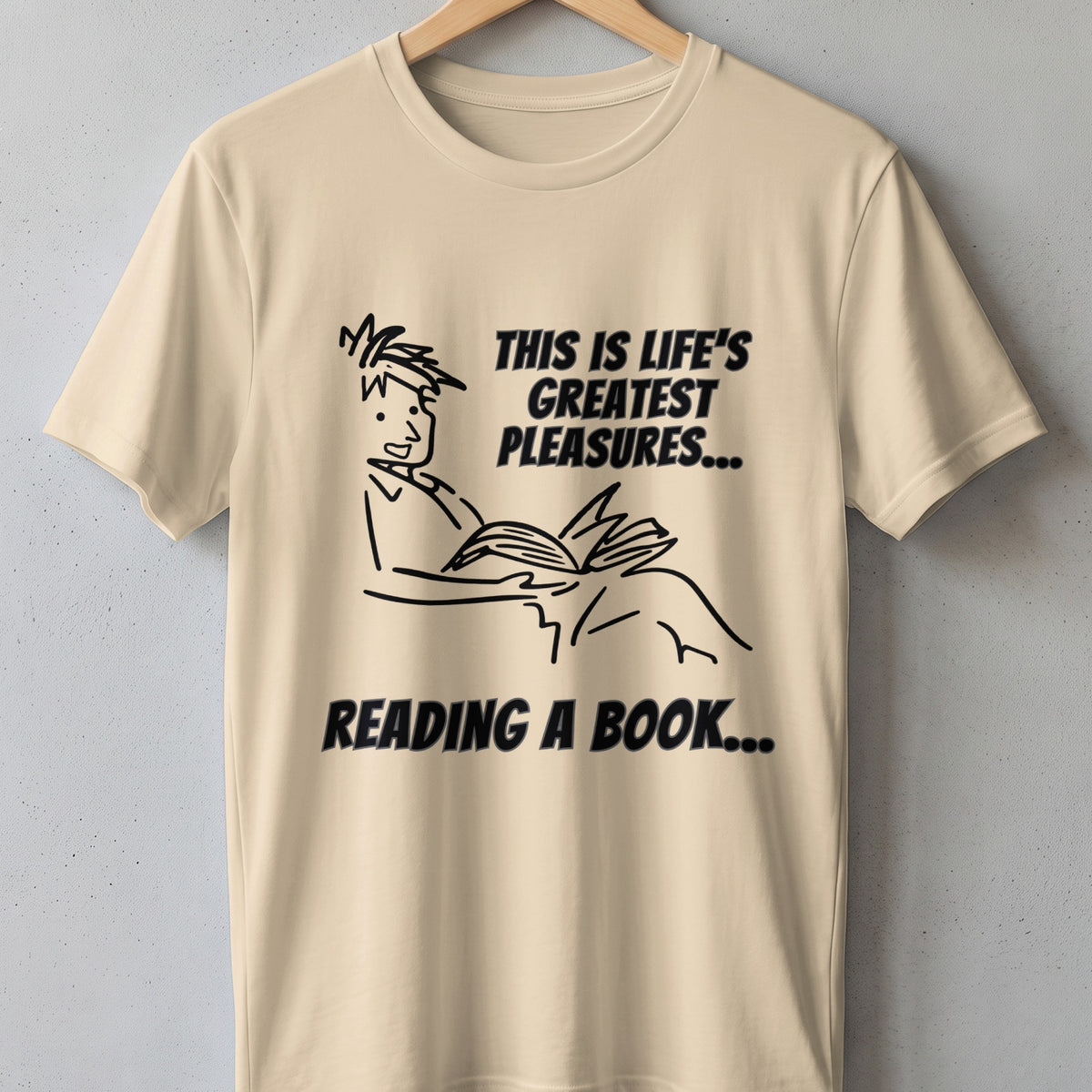 Cream t-shirt with line drawing of person reading and text "This is life's greatest pleasures... reading a book...".