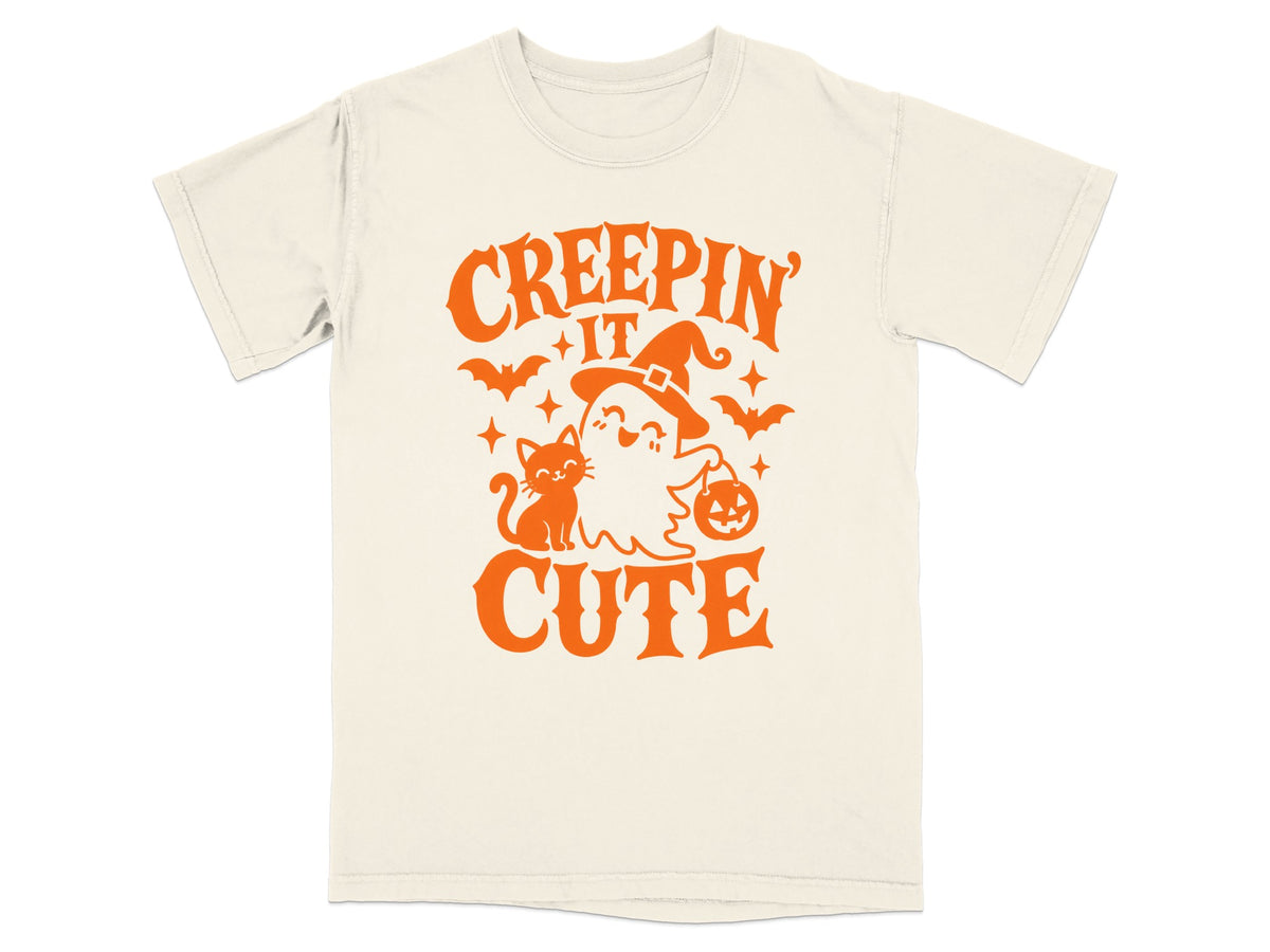 Cream t-shirt with orange text and graphics of a ghost, cat, pumpkin, and bats.