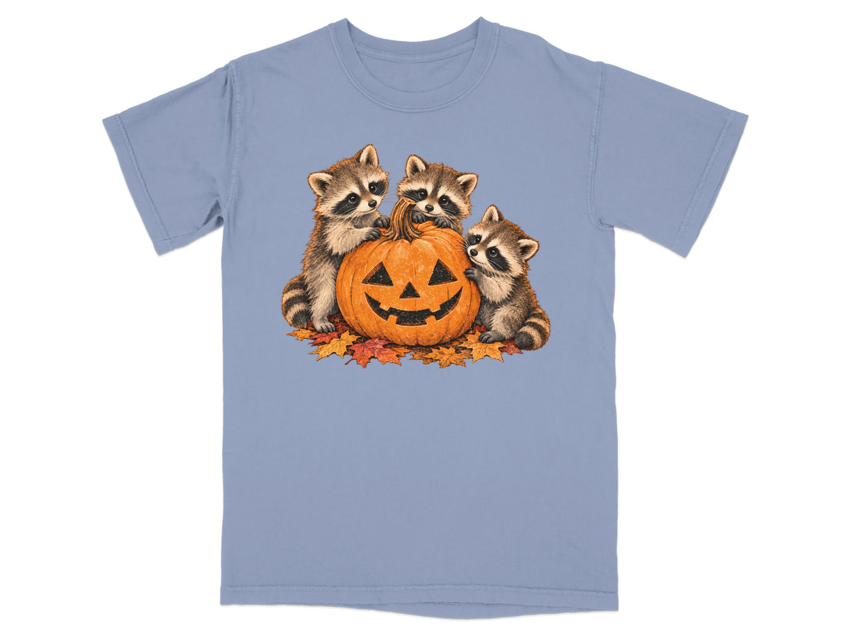 Three raccoons surround a carved jack-o'-lantern on fallen autumn leaves.