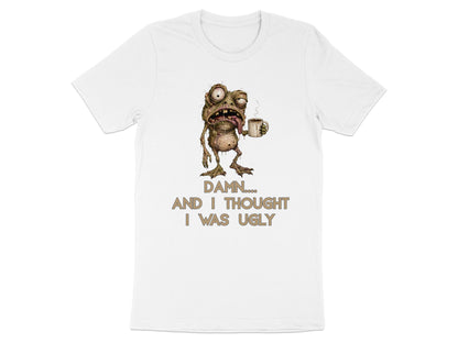 White t-shirt with cartoon monster holding coffee mug and text "Damn.... And I thought I was ugly."