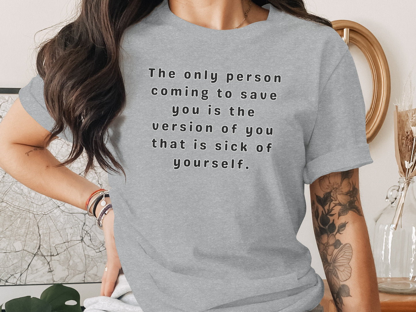 Grey t-shirt with black text: "The only person coming to save you is the version of you that is sick of yourself."