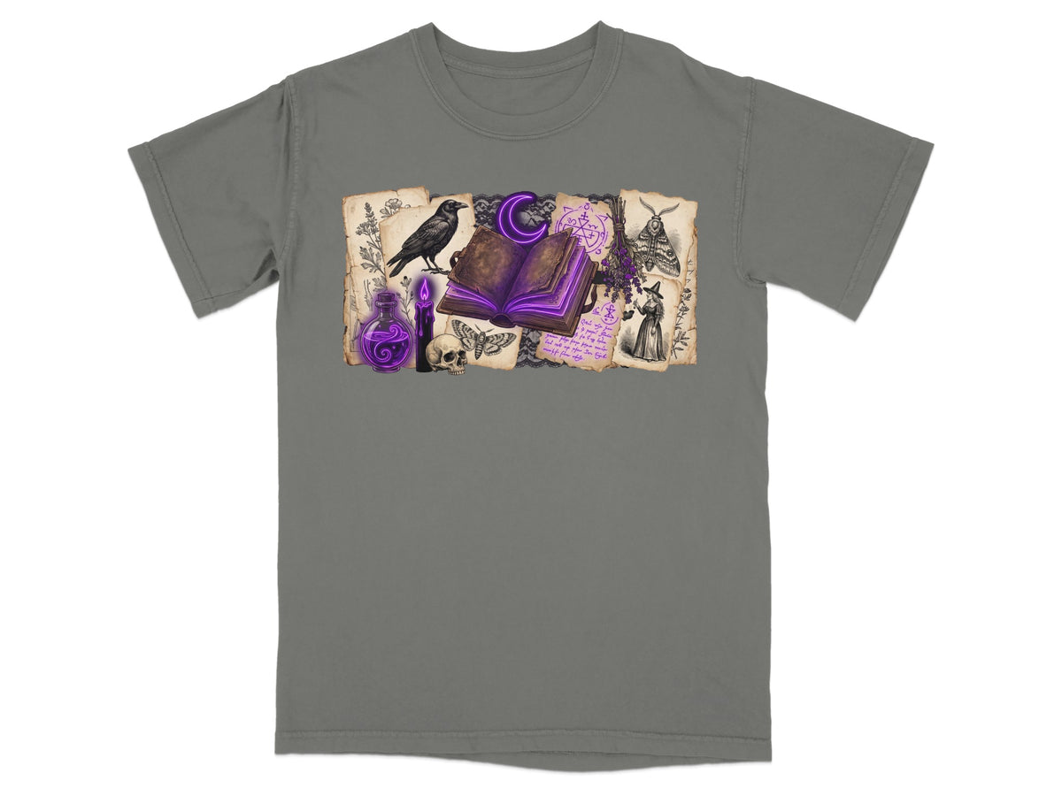 T-shirt with a dark grey base featuring a witchy illustration with a crow and open book.