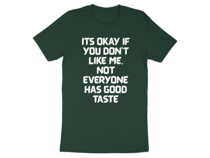 Dark green t-shirt with white text that reads "IT'S OKAY IF YOU DON'T LIKE ME. NOT EVERYONE HAS GOOD TASTE".