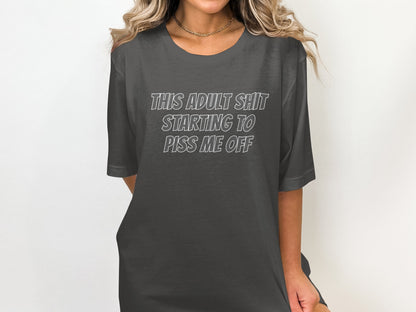 Dark gray t-shirt with white text that reads "THIS ADULT SHIT STARTING TO PISS ME OFF".