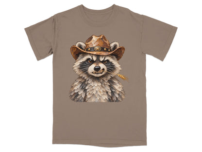 Raccoon wearing a cowboy hat with a wheat stalk in its mouth on a tan t-shirt.