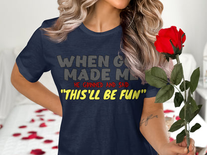 Dark navy t-shirt with text "WHEN GOD MADE ME HE GRINNED AND SAID "THIS'LL BE FUN"."