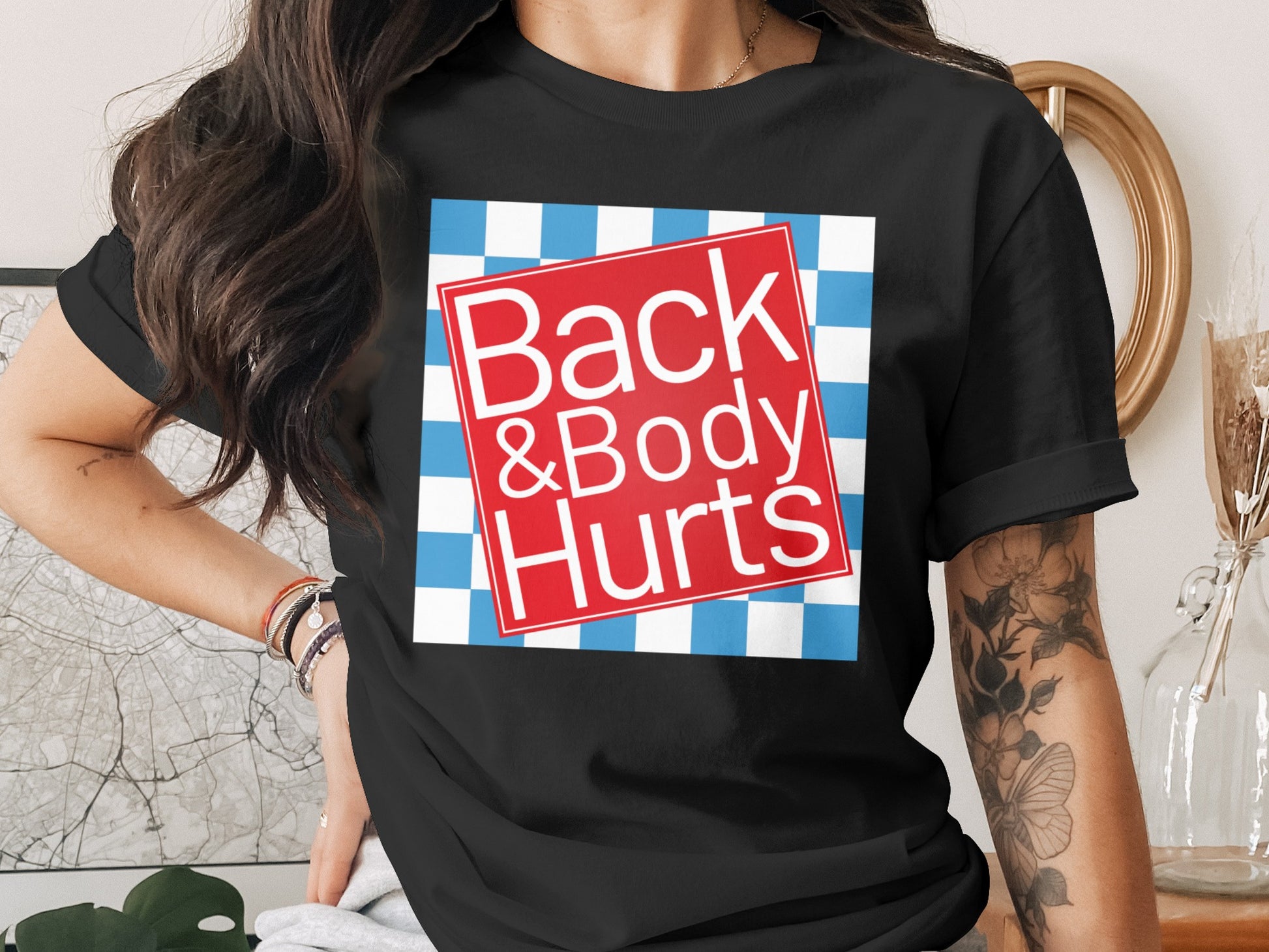 Black t-shirt with red and blue checkered graphic and text "Back & Body Hurts".