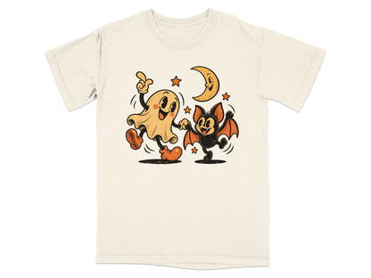 Ghost and bat dancing under a crescent moon and stars on a cream t-shirt.