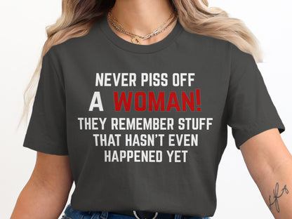 Dark grey t-shirt with white text "NEVER PISS OFF A WOMAN!" in red.