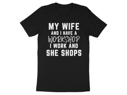 Black t-shirt with white text: "MY WIFE AND I HAVE A WORKSHOP I WORK AND SHE SHOPS"
