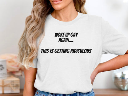 White t-shirt with black text that reads "WOKE UP GAY AGAIN.... THIS IS GETTING RIDICULOUS"