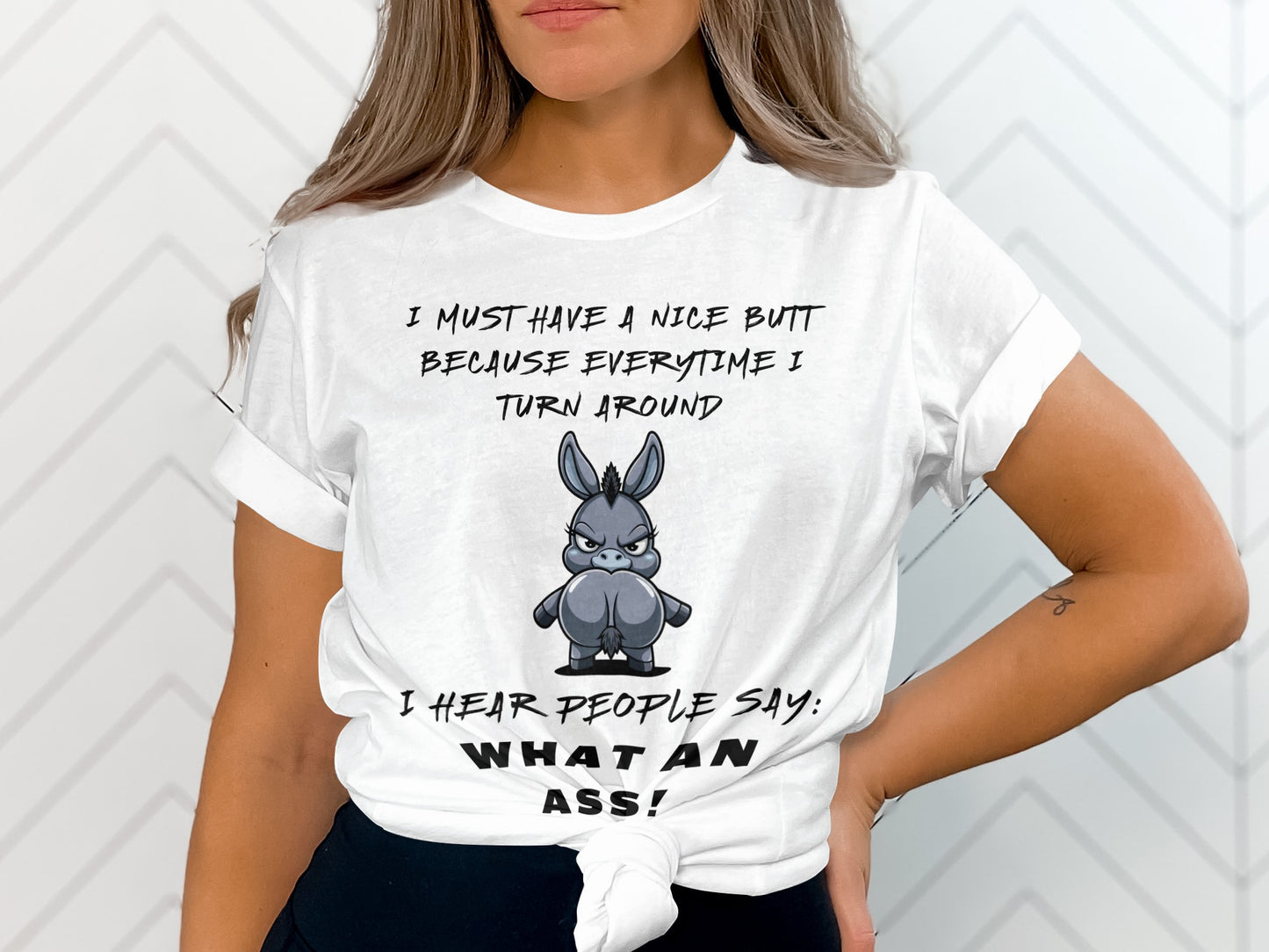 White t-shirt with text and cartoon donkey illustration: "I must have a nice butt because everytime I turn around I hear people say: What an ass!"