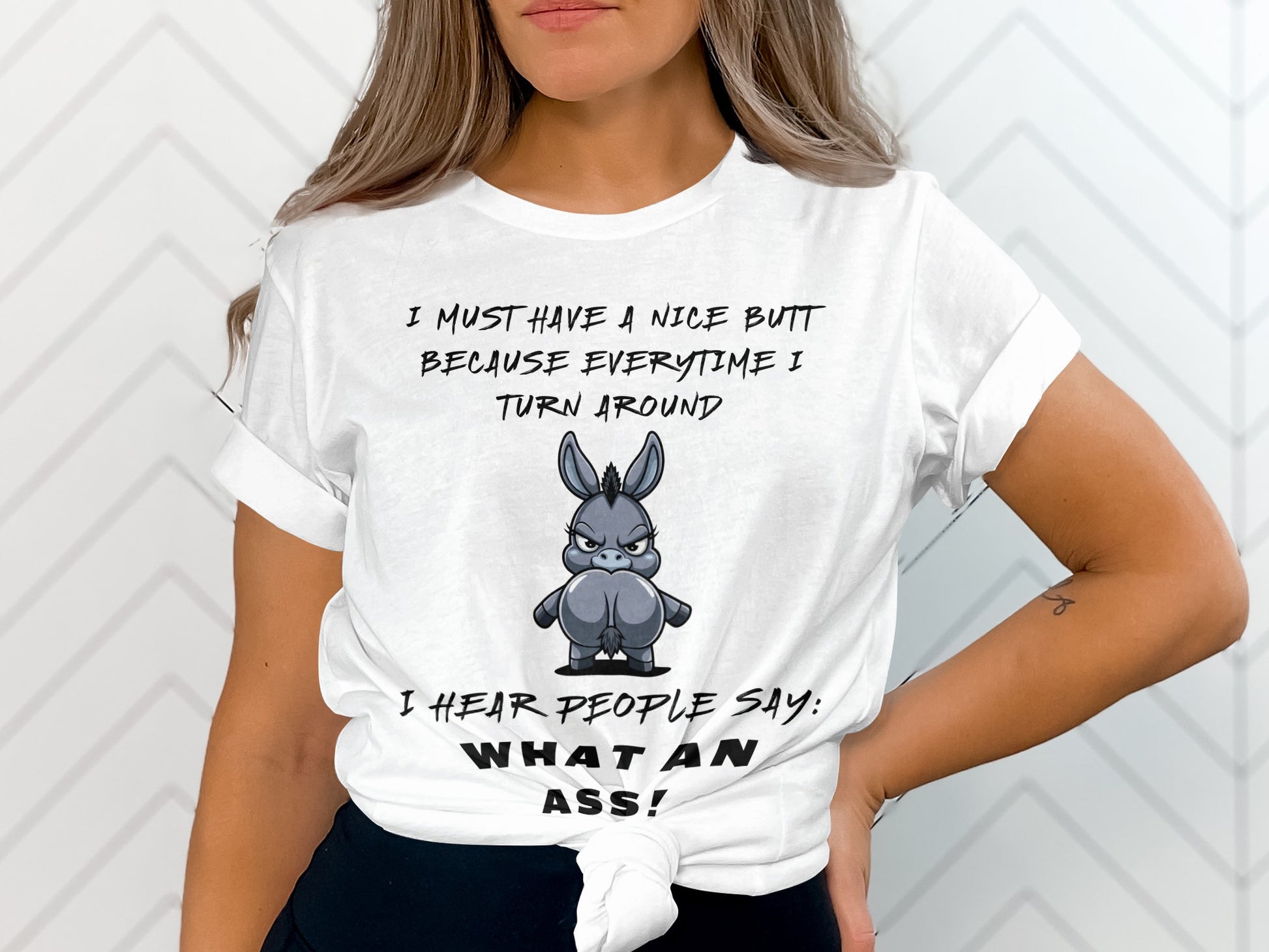 White t-shirt with text and cartoon donkey illustration: "I must have a nice butt because everytime I turn around I hear people say: What an ass!"