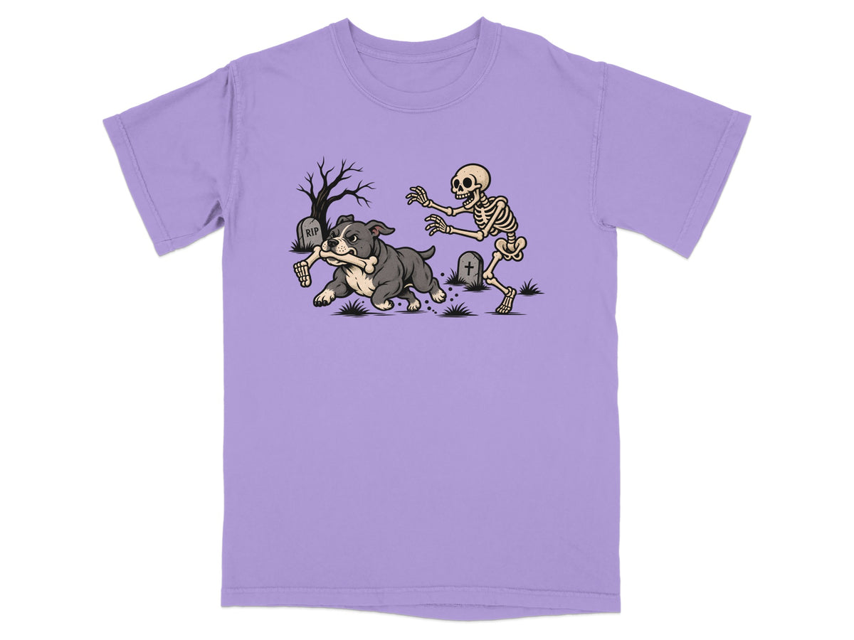 A purple short-sleeved t-shirt featuring a graphic of a skeleton chasing a dog running with a bone.