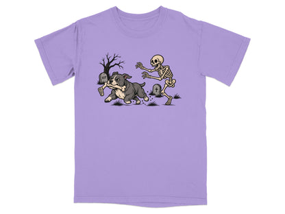 A purple short-sleeved t-shirt featuring a graphic of a skeleton chasing a dog running with a bone.