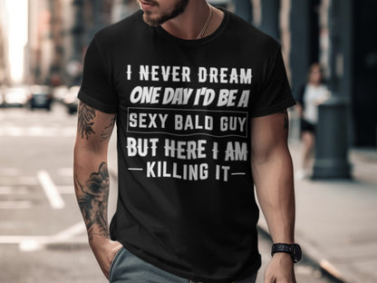 Black t-shirt with text "I NEVER DREAM ONE DAY I'D BE A SEXY BALD GUY BUT HERE I AM KILLING IT".