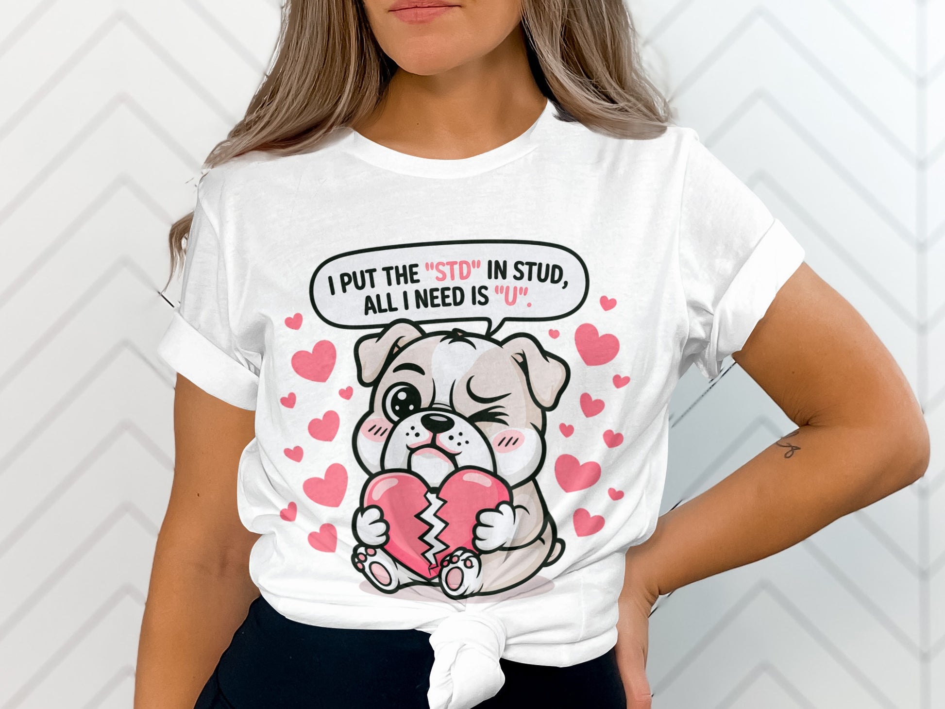White t-shirt with a cartoon bulldog holding a broken heart, text reads "I PUT THE 'STD' IN STUD, ALL I NEED IS 'U'".