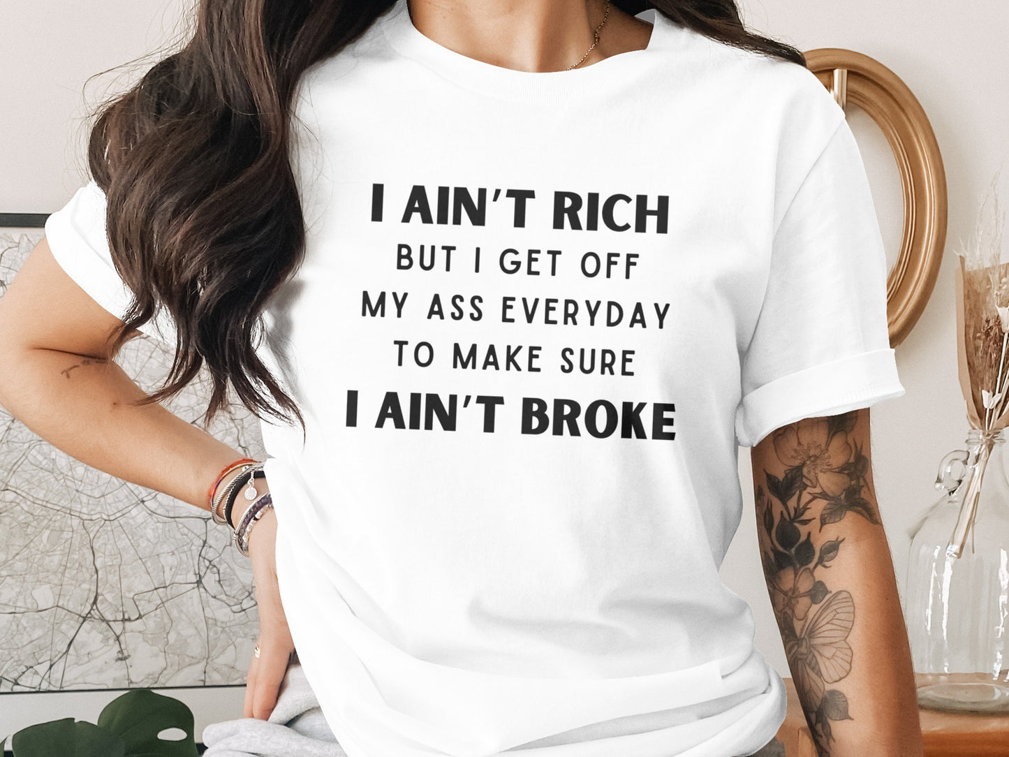 White t-shirt with black text that reads "I ain't rich but I get off my ass everyday to make sure I ain't broke."