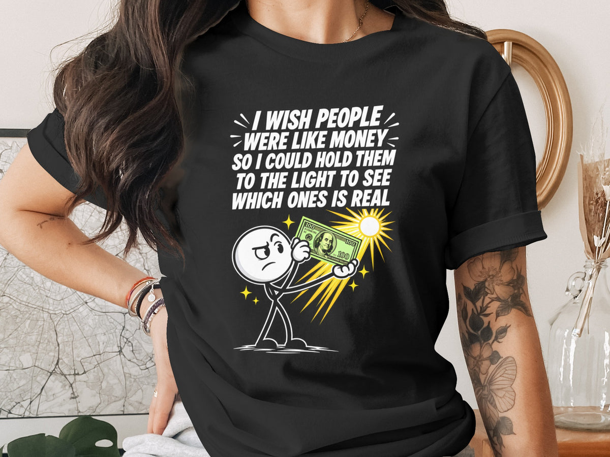 Black t-shirt with text and cartoon holding a $100 bill to the light.