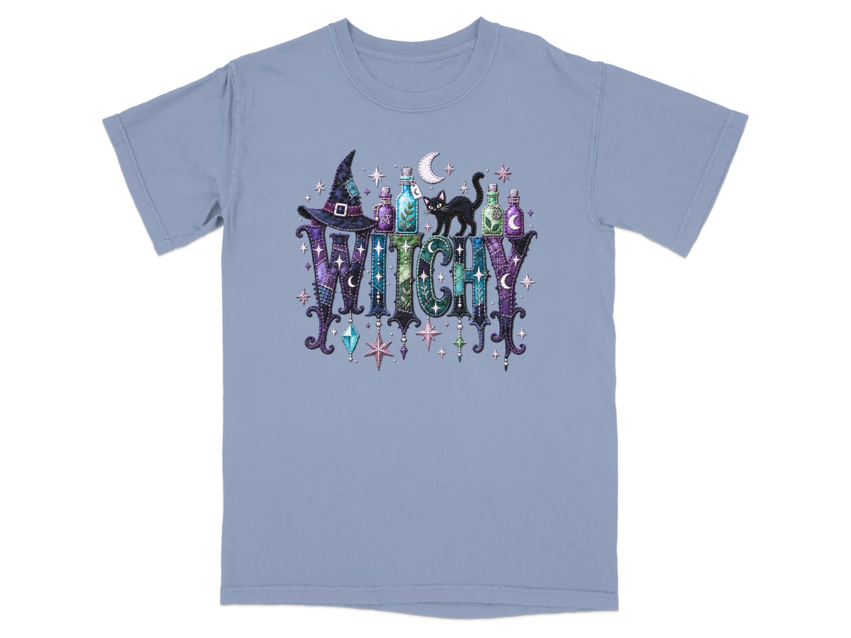 A blue t-shirt with the word "WITCHY" in a colorful, textured font with Halloween-themed graphics.