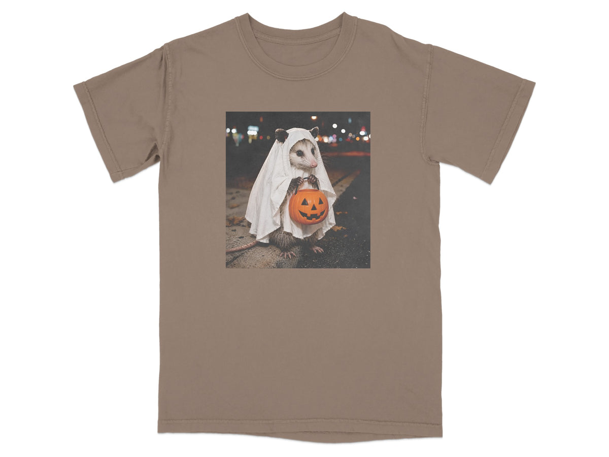 Opossum in ghost costume holding a jack-o-lantern bucket at night.