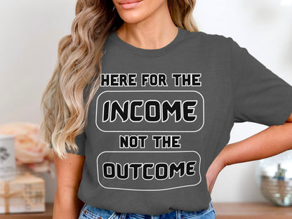 Dark grey t-shirt with white text "HERE FOR THE INCOME NOT THE OUTCOME".