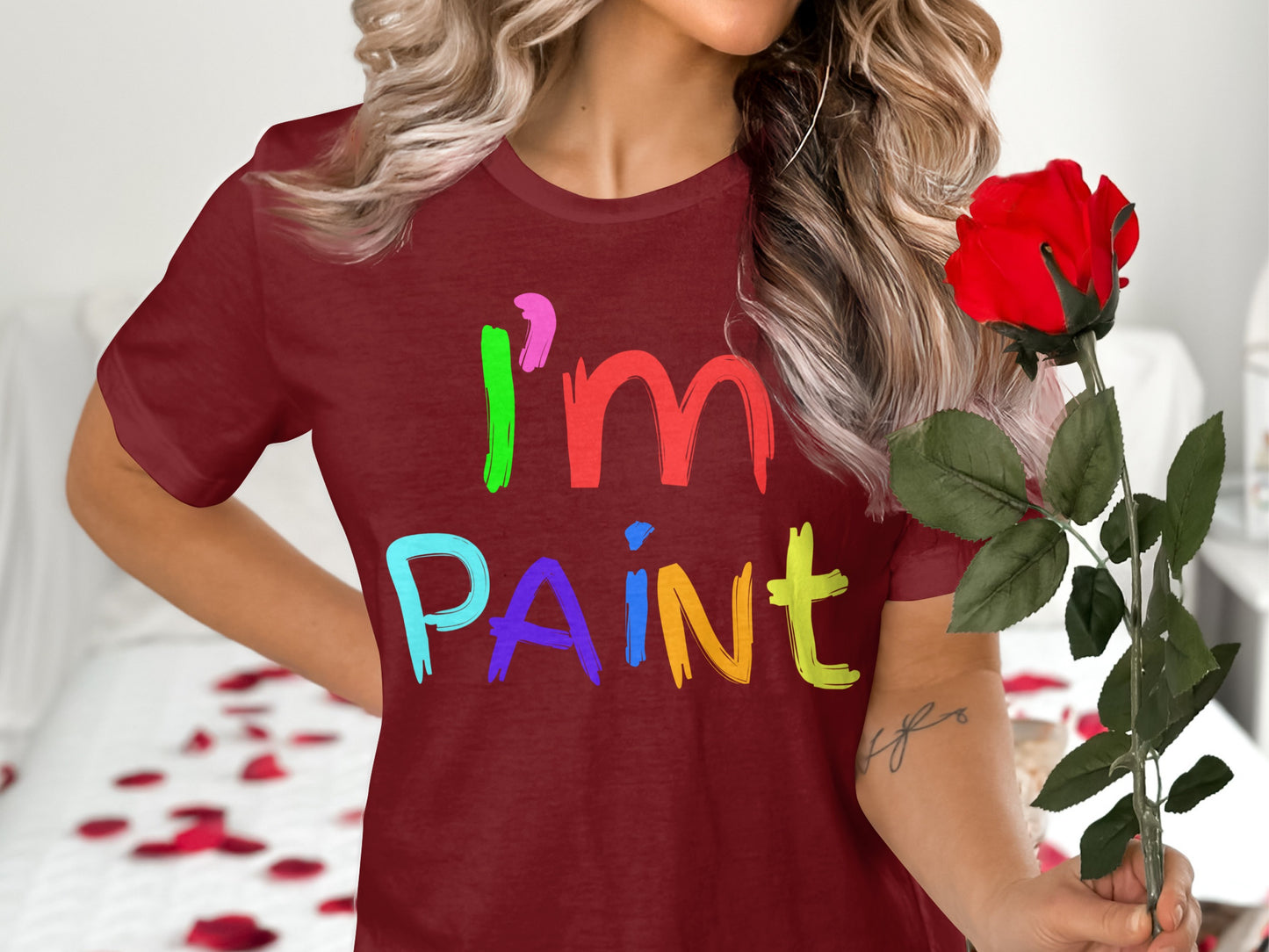Maroon t-shirt with colorful text "I'm PAINT", holding a red rose.