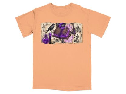 Peach t-shirt with a graphic of a witch, raven, open spellbook, and occult symbols.