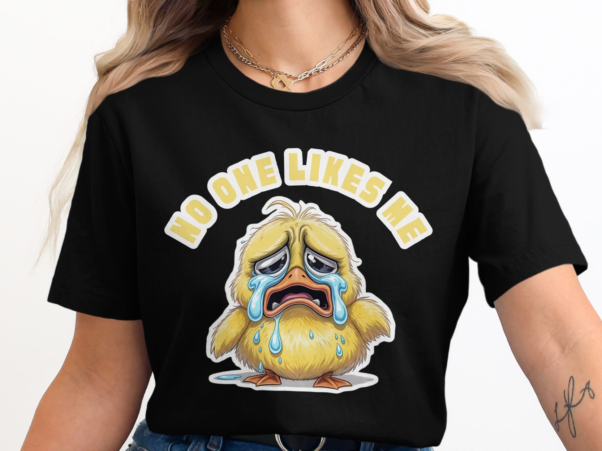 Black t-shirt featuring a crying yellow chick and text "NO ONE LIKES ME".