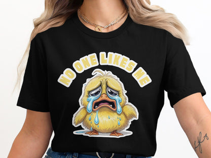 Black t-shirt featuring a crying yellow chick and text "NO ONE LIKES ME".
