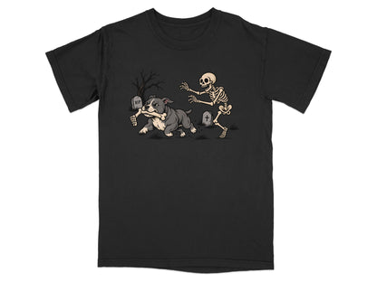 A black t-shirt features a graphic of a grey bulldog running away with a skeleton arm in a graveyard.