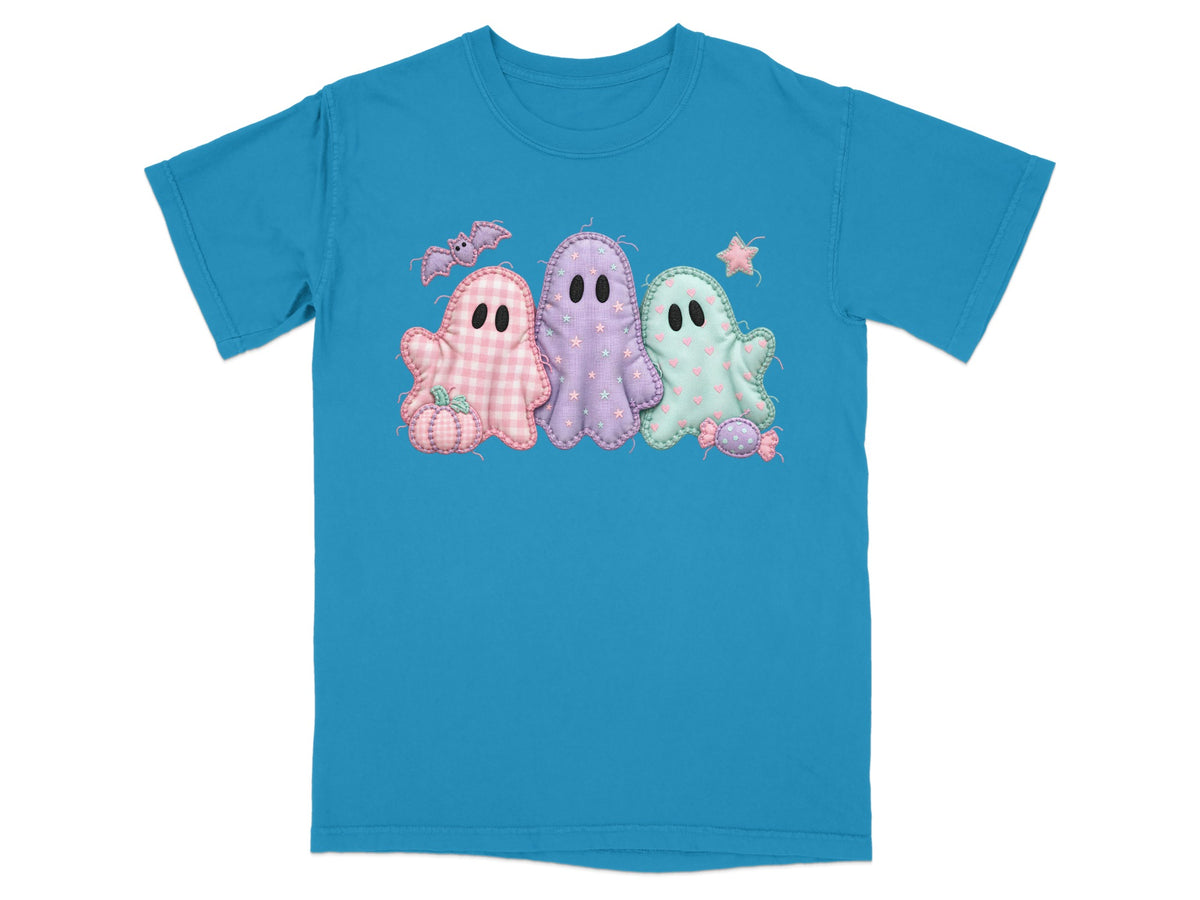 Three pastel ghost appliqués on a blue t-shirt with Halloween accents.