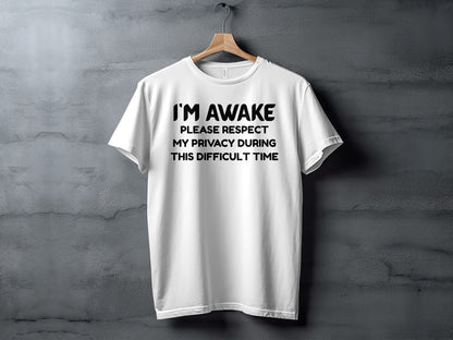 White t-shirt with black text that reads "I'M AWAKE PLEASE RESPECT MY PRIVACY DURING THIS DIFFICULT TIME".