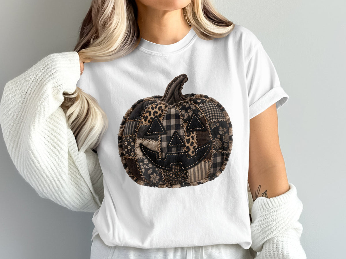 White t-shirt with a black and brown patchwork jack-o-lantern graphic.