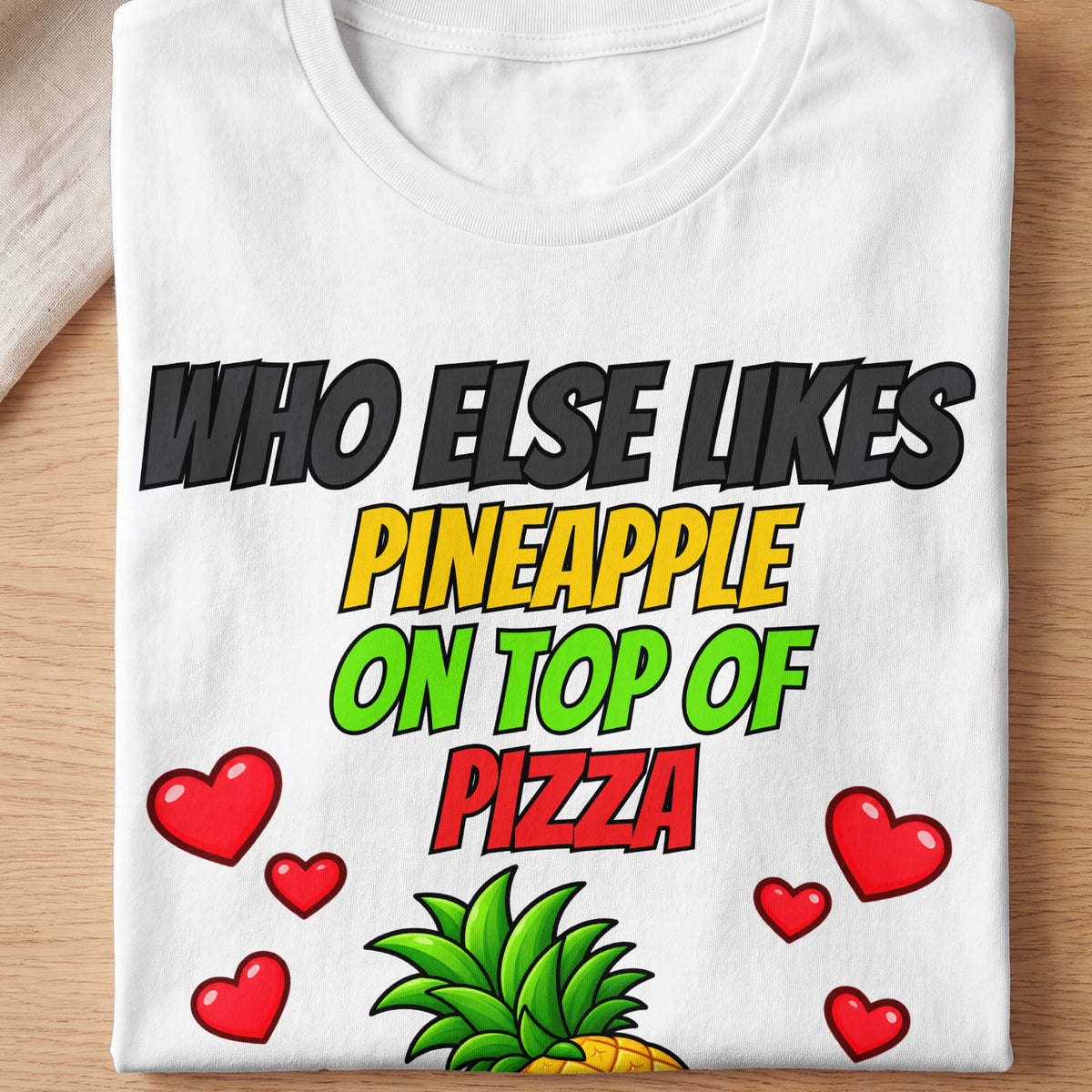 White t-shirt with text "WHO ELSE LIKES PINEAPPLE ON TOP OF PIZZA", hearts, and pineapple.