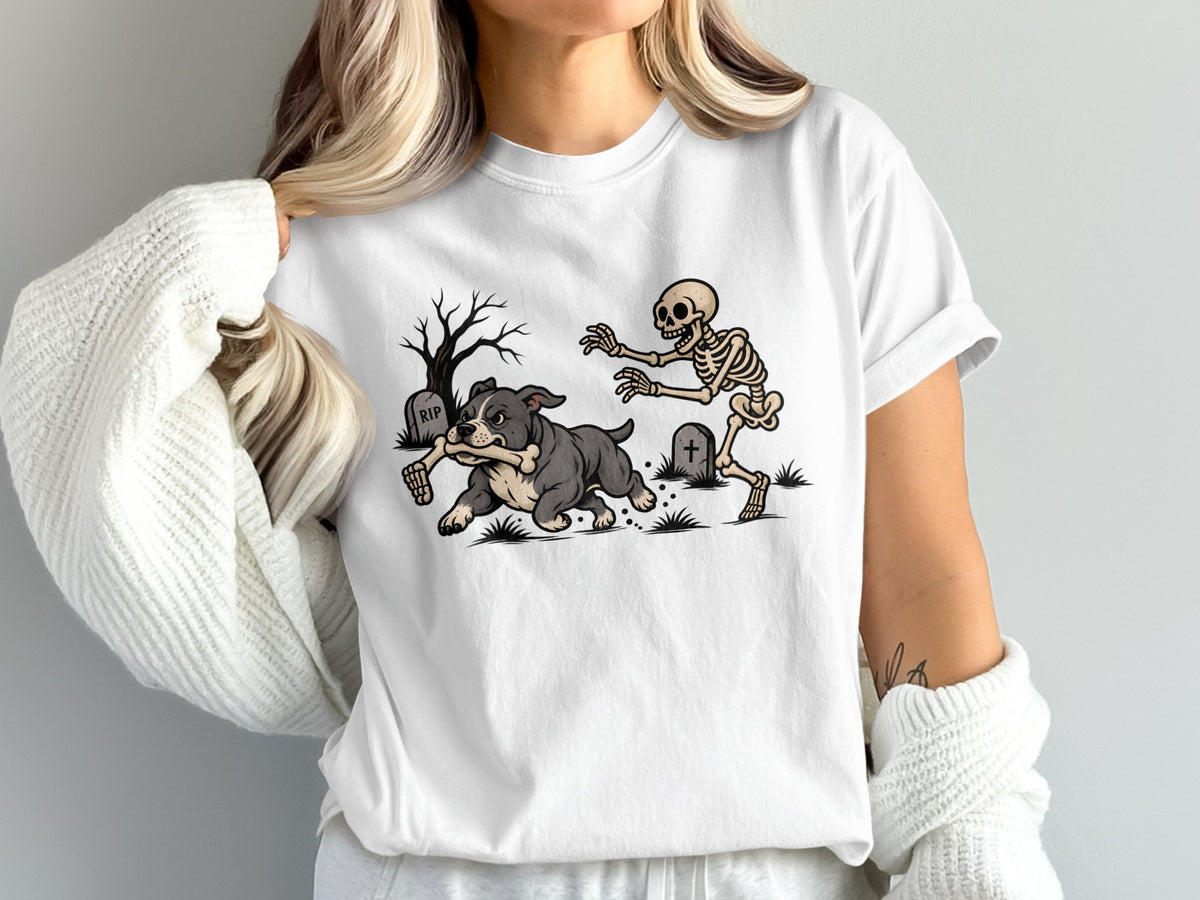 A woman wearing a white t-shirt featuring a graphic of a skeleton chasing a dog running with a bone.