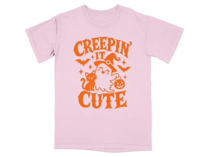 Pink t-shirt with orange graphic of "Creepin' It Cute" featuring a ghost, cat, and bats.