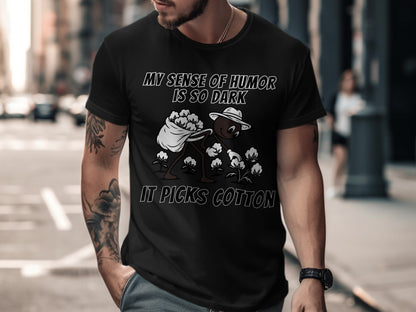 Black t-shirt with text "MY SENSE OF HUMOR IS SO DARK IT PICKS COTTON" and graphic.