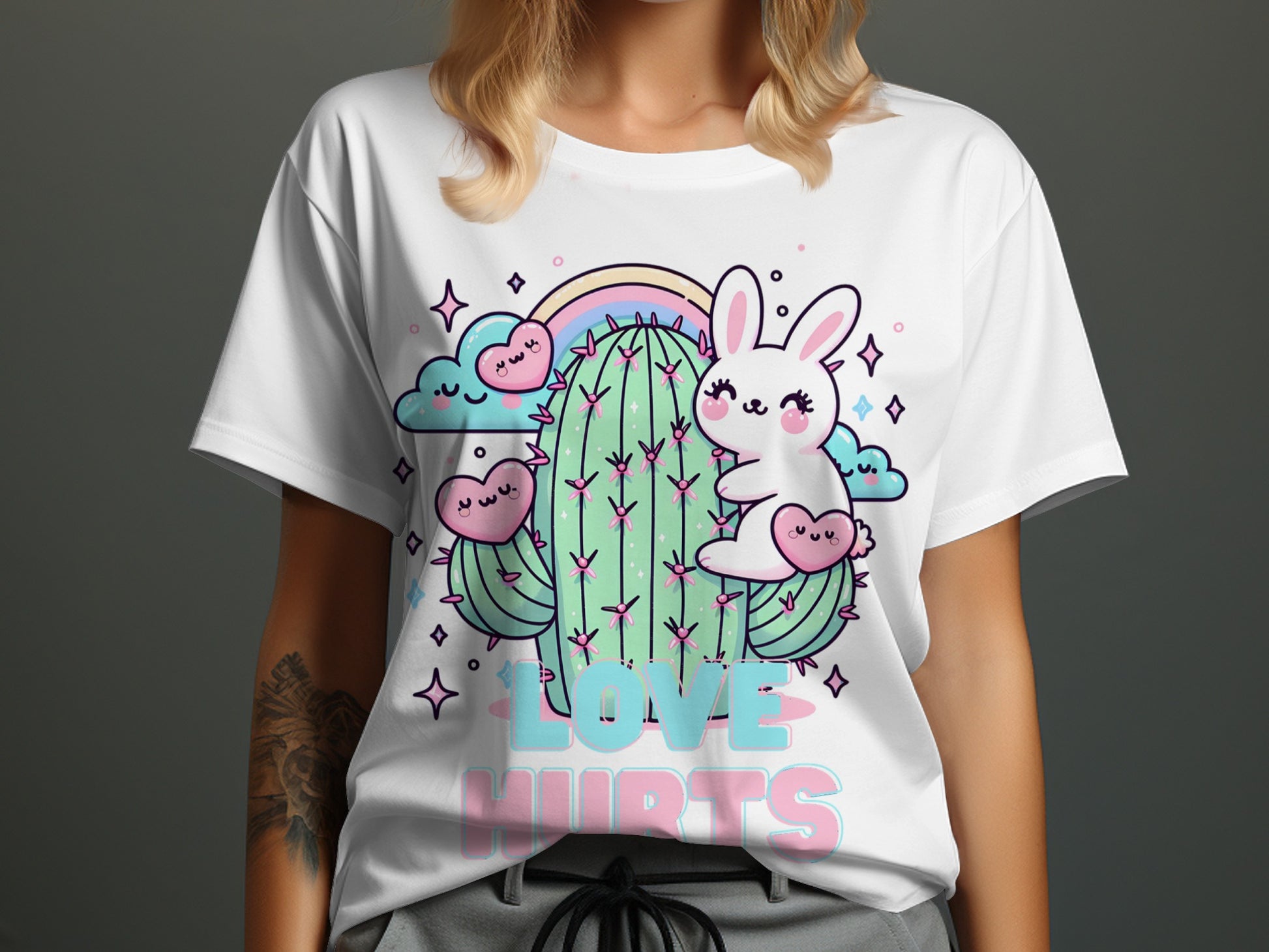 White t-shirt with kawaii cartoon rabbit and cactus, rainbow, clouds, hearts, and text "LOVE HURTS".