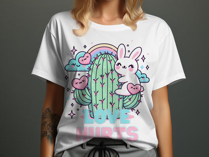 White t-shirt with kawaii cartoon rabbit and cactus, rainbow, clouds, hearts, and text "LOVE HURTS".