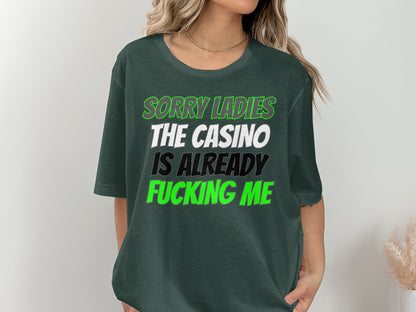Green t-shirt with white, black, and green text that reads "Sorry ladies the casino is already fucking me".