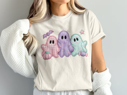 Three pastel stitched ghosts with Halloween motifs on a cream t-shirt.