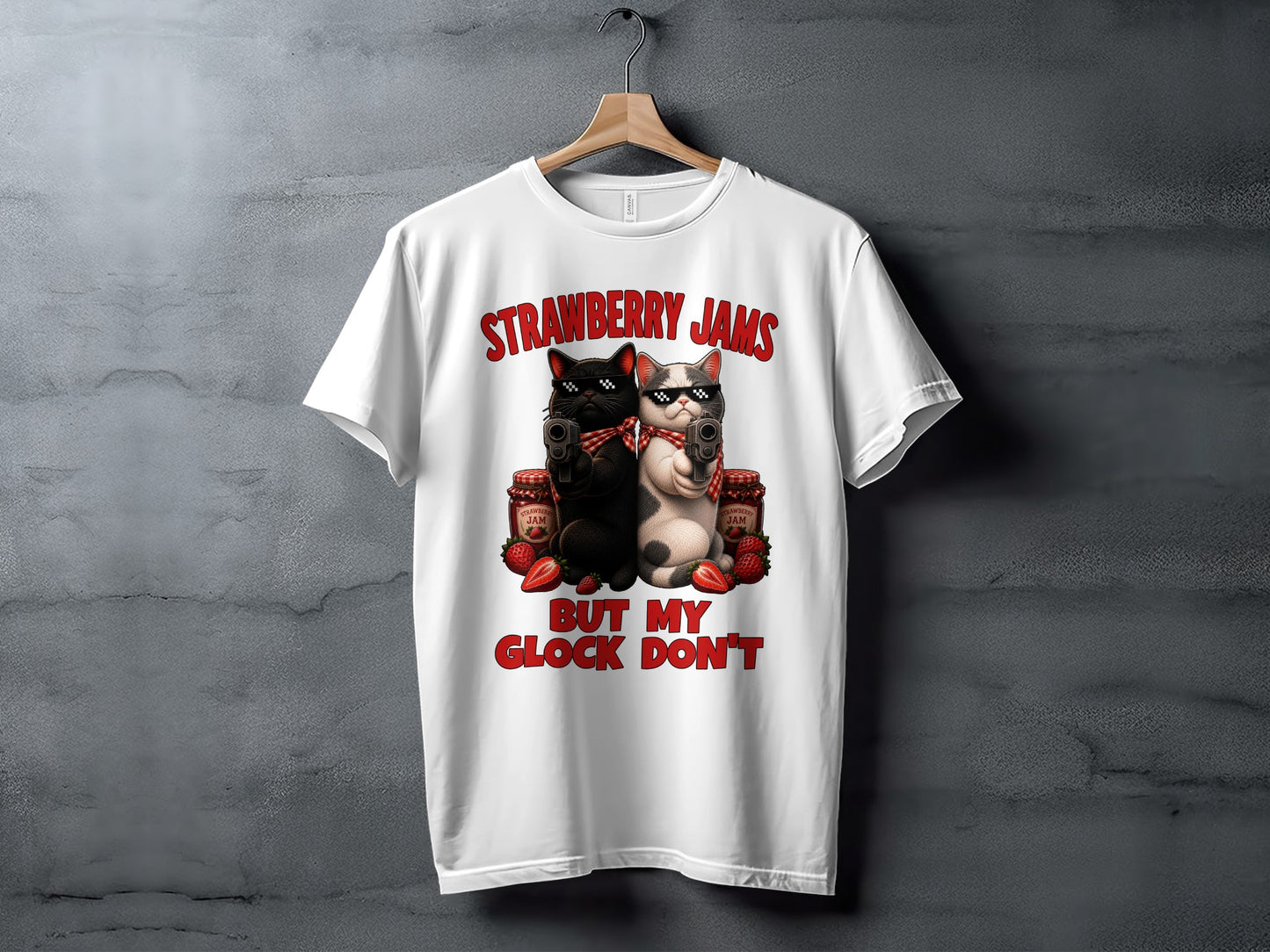 White t-shirt with graphic of two cats holding guns, jars of jam, and strawberries, text reads "Strawberry Jams But My Glock Don't".